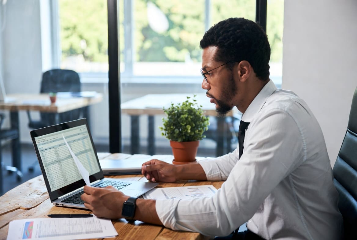 Small-business owner reviewing a cyber insurance policy on a laptop, considering AI fraud coverage gaps
